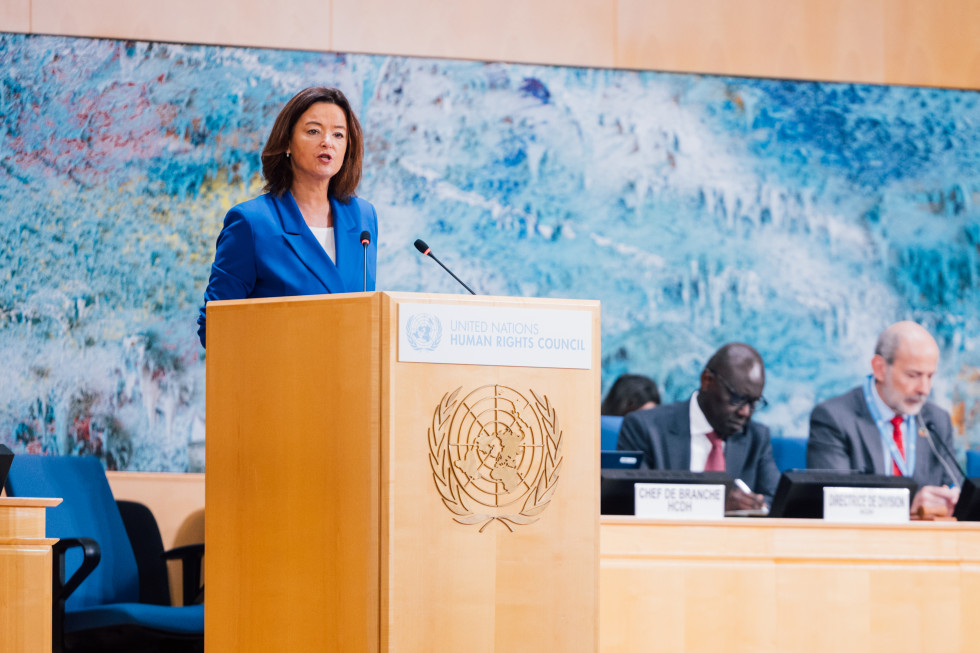 Ministrica stoji za govorniškim pultom in govori.