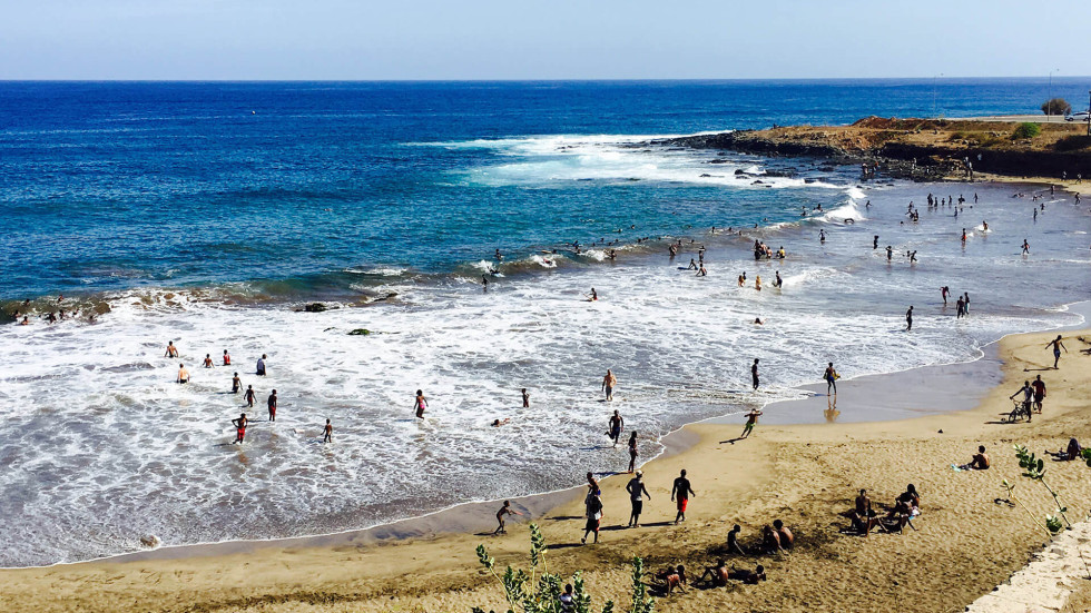 people on a sandy beach and in the sea from afar
