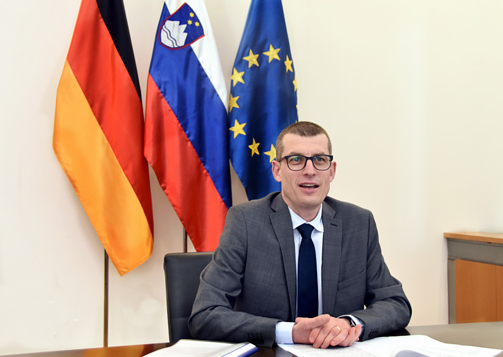 state secretary sitting in front of flags