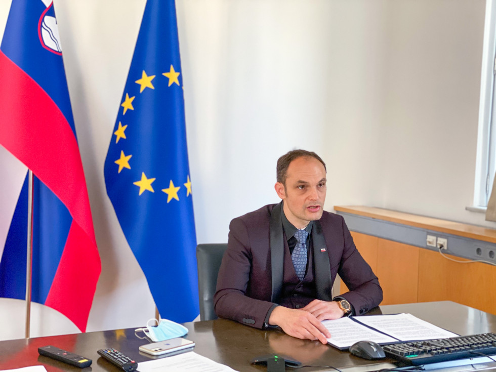 Minister is sitting at the table with flags behind