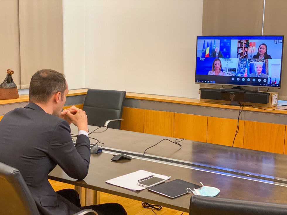 minister at his desk with computer and participants on screen