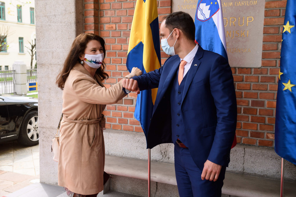 ministers saying hello with elbows with flags behind