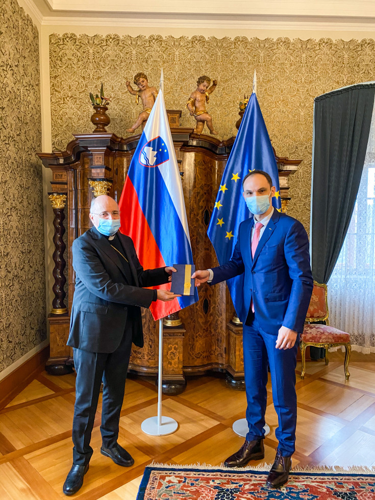 Anže Logar presenting novel to Doyen of the Diplomatic Corps in Slovenia, the Apostolic Nuncio to Slovenia, Jean-Marie Speich