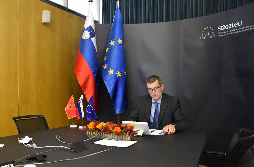 during the conference, sitting at a table, flags behind