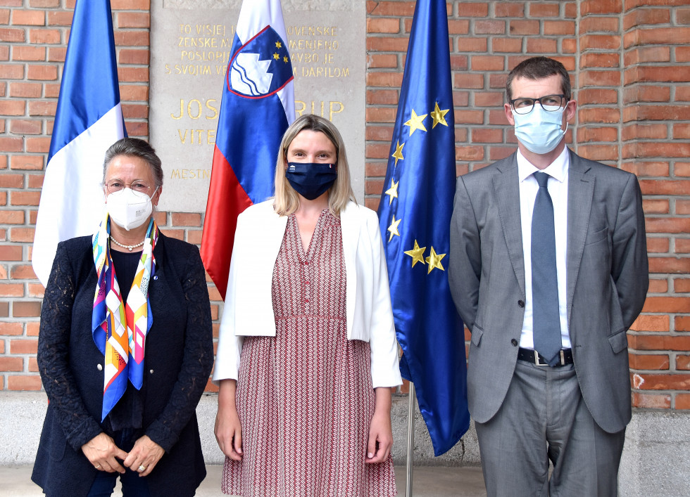 Udeleženci srečanja stojijo pred zastavami Francije, Slovenije in EU