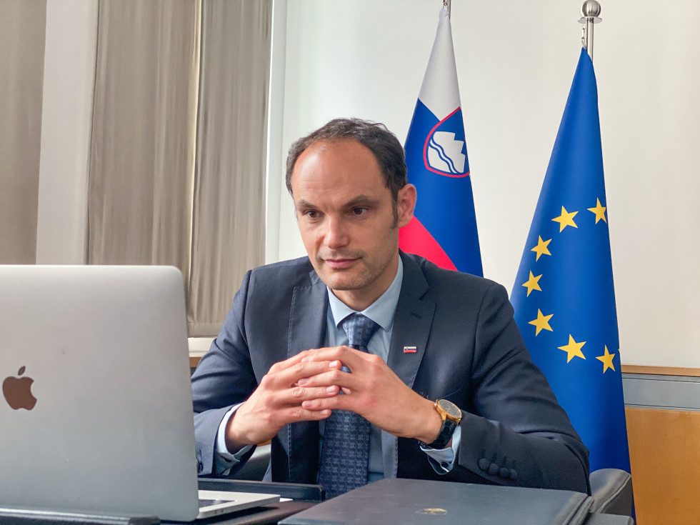 sedi pred računalnikom, zadaj zastave