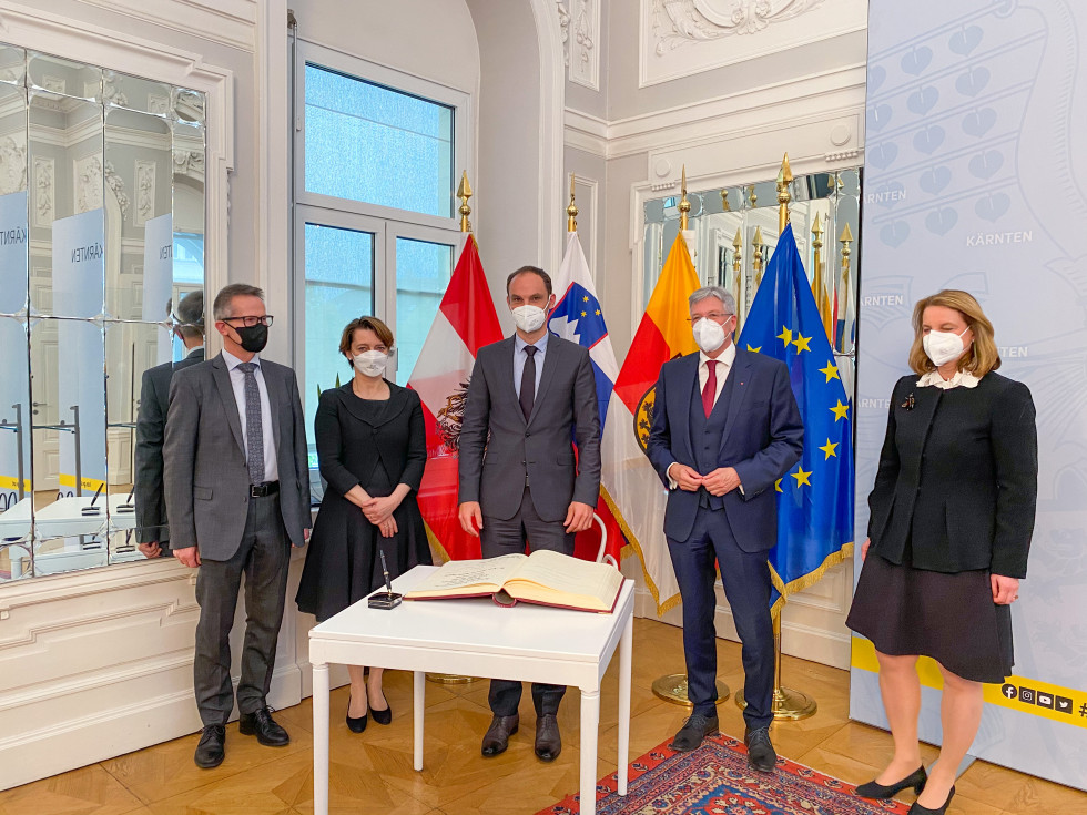 Minister and representatives standing in front of flags, small table with book in front