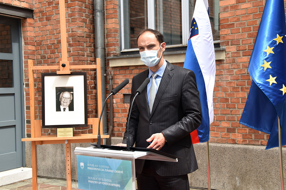 standing, speaking, falgs behind, photograph on the left