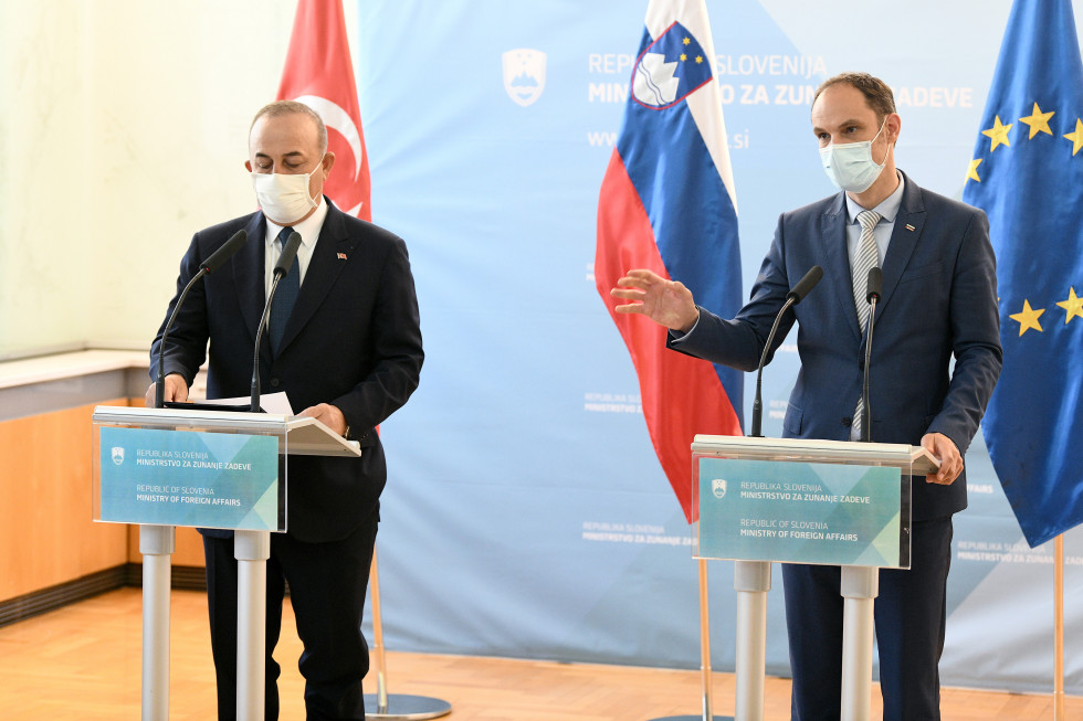 Ministers during press conference, flags behind