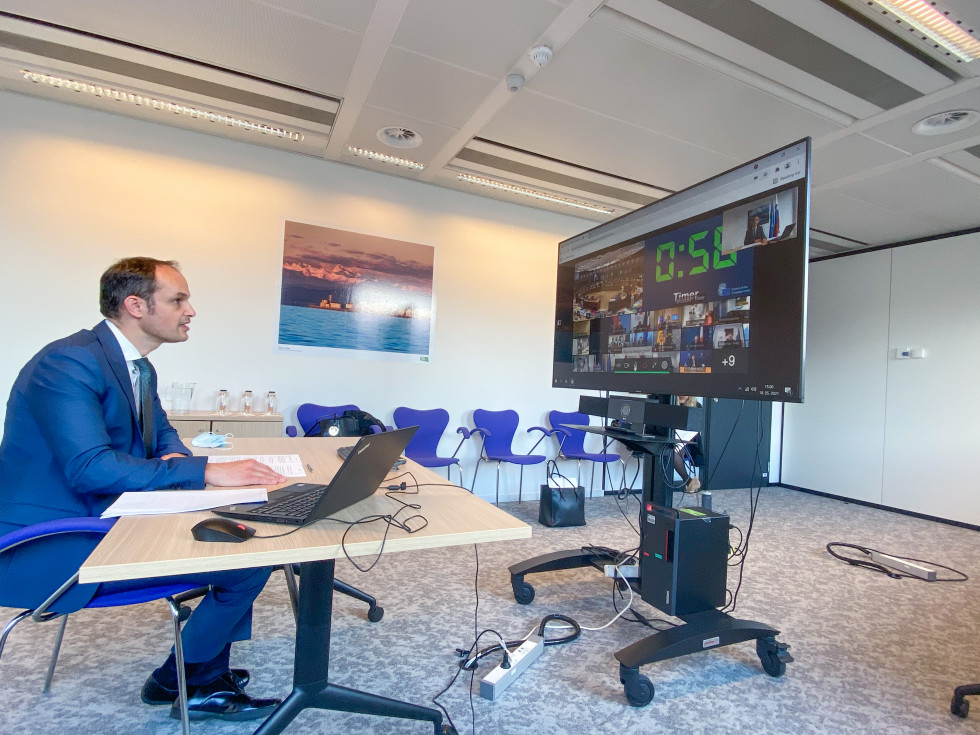 minister by computer, with screen and participants, sitting at the desk