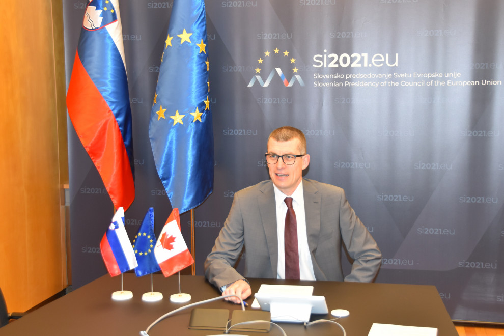 state secretary Dovžan sitting at the table, behind pano Eu2021SI and flags
