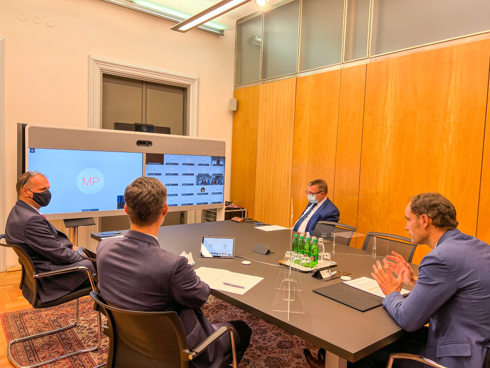 minister Logar sits at the table and has talks via audio-video conference