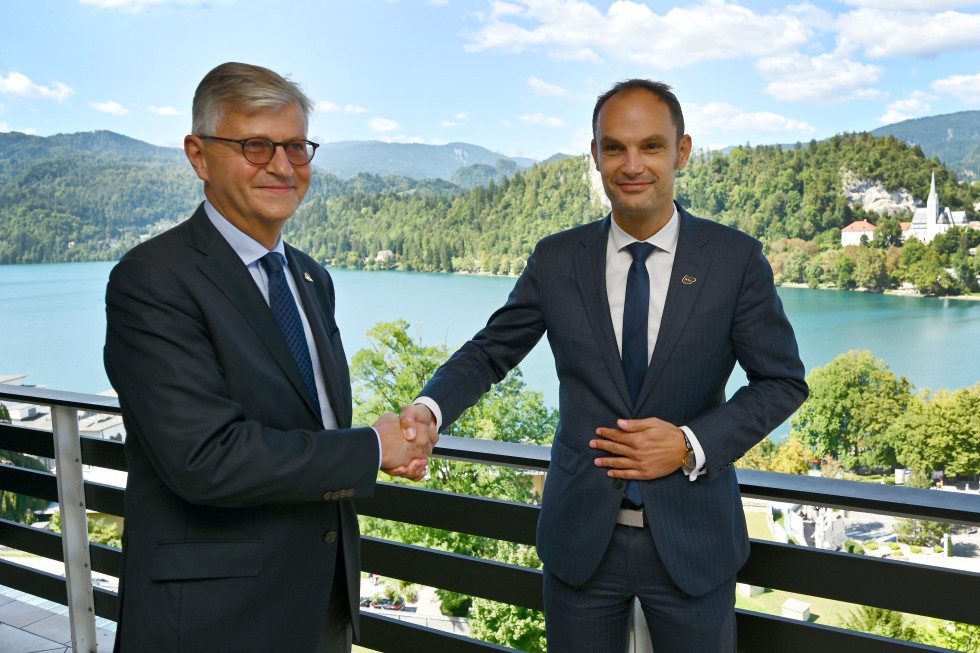 standing on a balcony shaking hands with a view of a lake and greenery behind