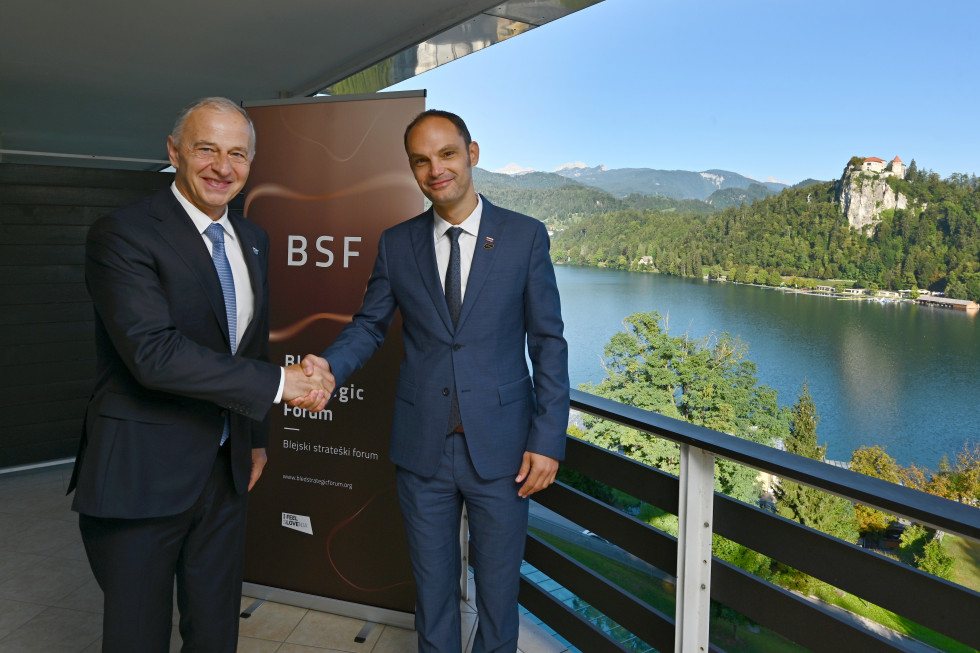 standing on a balcony, shaking hands, lake behind