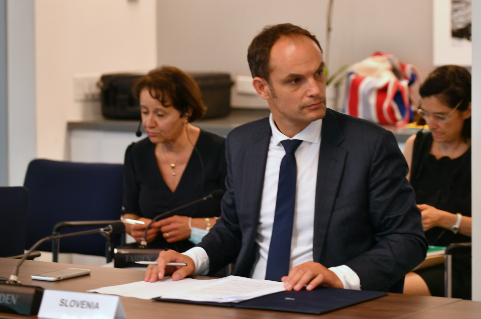 minister med srečanjem sedi za mizo pred papirji