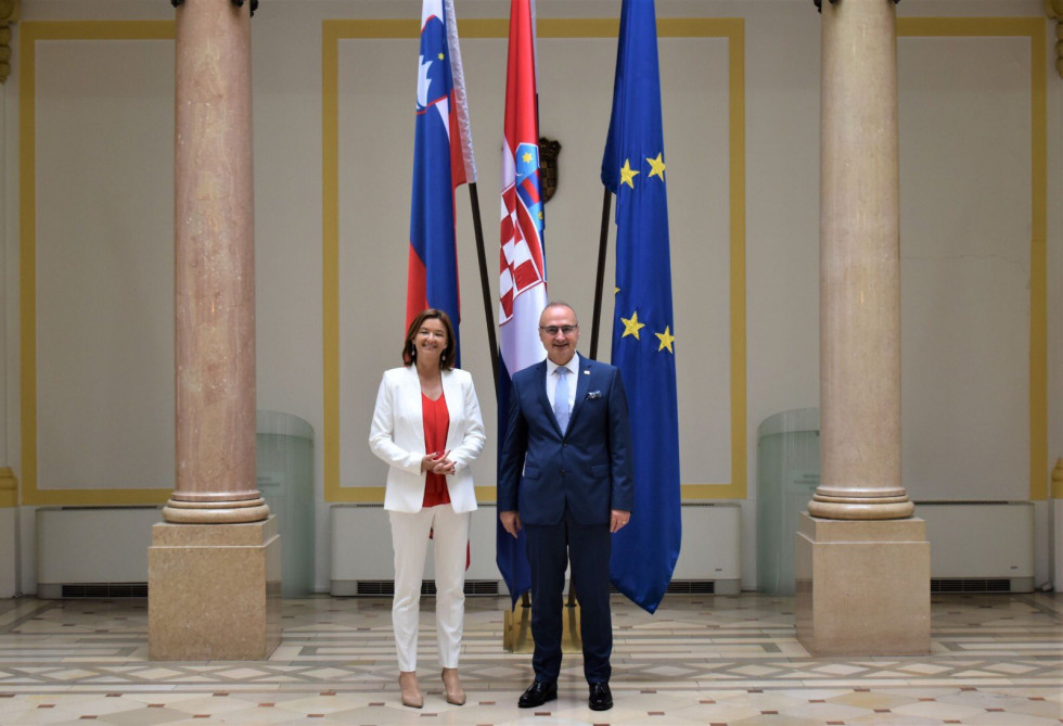 Minister Fajon and Minister Grlić Radman, standing in front of flags