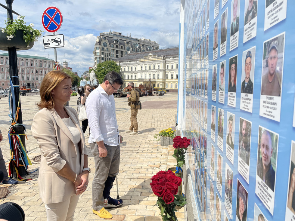 Ministrica Fajon in minister za zunanje zadeve Ukrajine Dmiter Kuleba stojita pred zidom spomina na padle v vojni v Donbasu