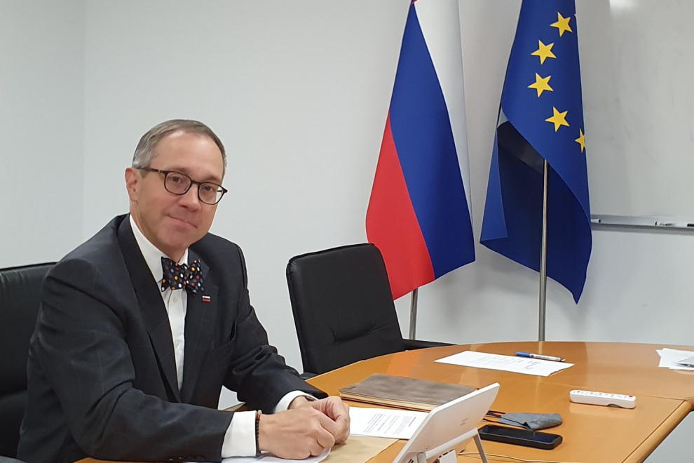 Blaž Košorok za pisalno mizo, v ozadju slovenska in EU zastava