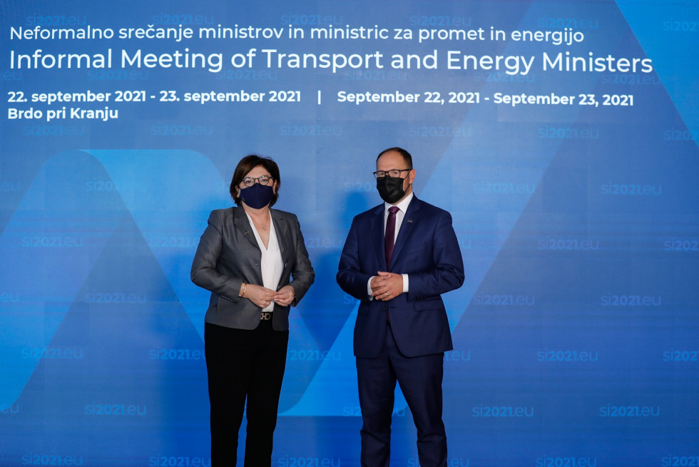 Komisarka za promet Adina Vălean z ministrom Jernejem Vrtovcem pred panojem na Brdu, z maskami.