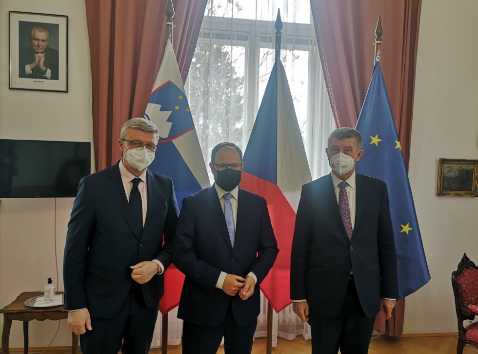 Minister stoji pred Češko in Slovensko zastavo poleg premierja in ministra
