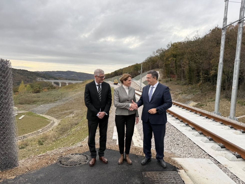 V ozadju trasa drugega tira, tiri in viadukt. V ospredju ministrica, direktor 2TDK Matej Oset in evropski komisar Cicikostas.