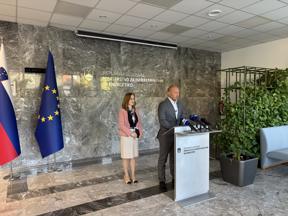 Moški stoji za govorniškim pultom in daje izjavo. 