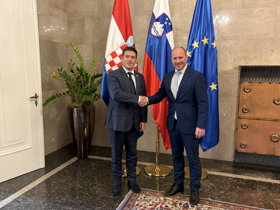 Minister Oleg Butković in minister Jernej Vrtovec med rokovanjem pred zastavami