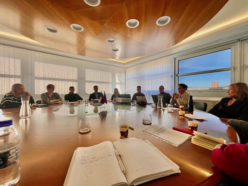 Revizorji v Mariboru sedijo v sejni sobi in se pogovarjajo.