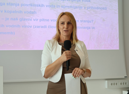 Direktorica urada; Govorka z mikrofonom nagovarja udeležence strokovnega dogodka.
