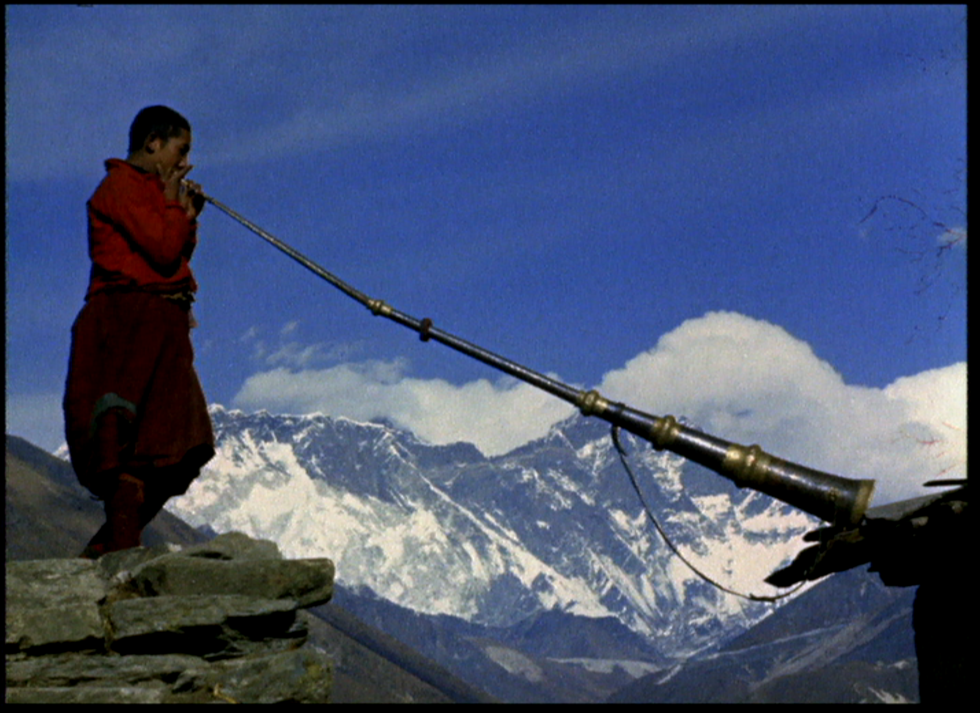 A sherpa with a horn, in the snow-capped mountains. 