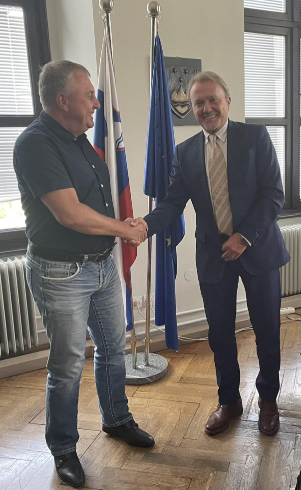 Dr. Bojan Cvelfar in dr. Emil Krstetski se rokujeta v pisarni, v ozadju visita zastavi Slovenije in EU