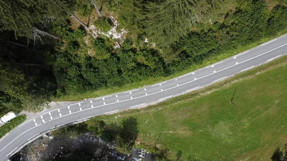Posnetek ceste v gozdu iz zraka, kjer so izvedene nove talnih označb za motoriste.