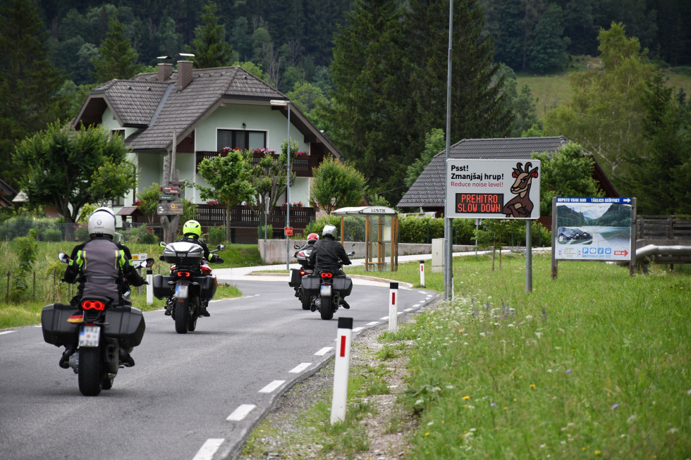 Štirje motoristi v naselju. Prikazovalnik "Prehitro. Slow down".