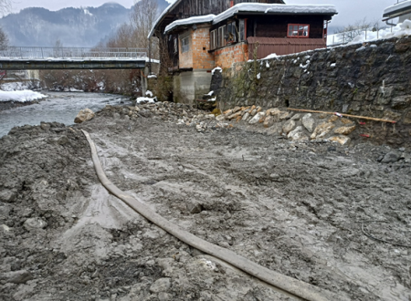 Blatna brežina reke Sore, v ozadju pa stavba