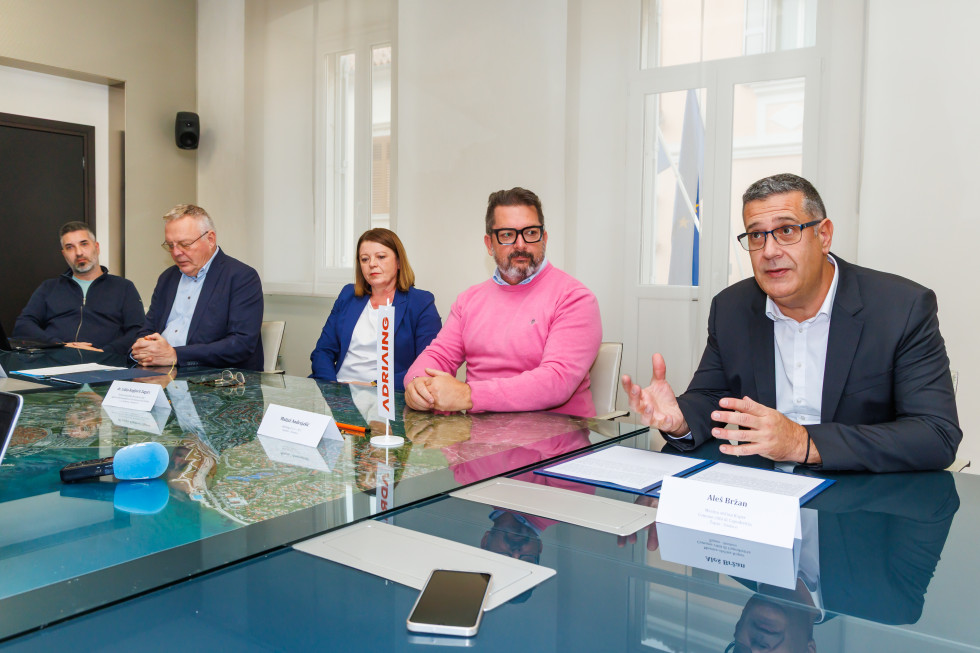 Župan Aleš Bržan sedi za mizo in nagovarja navzoče.