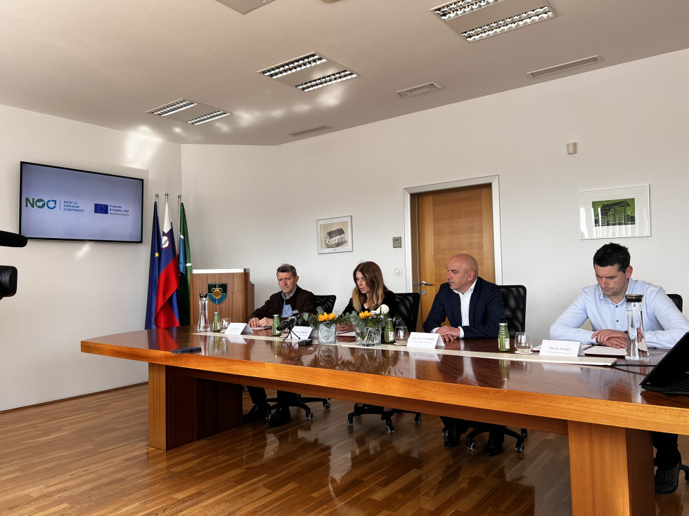 Sejna soba z mizo za katero sedijo trije moški in ženska