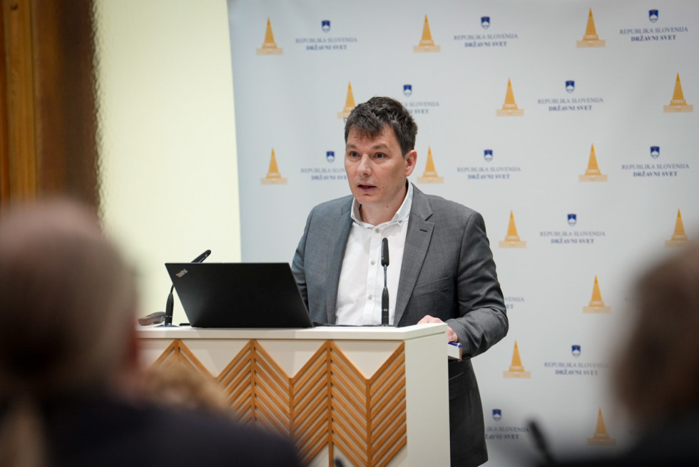 Rok Velišček za govorniškim pultom med predstavitvijo.