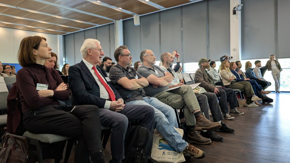 Udeleženci sedijo v občinstvu in spremljajo dogodek v konferenčni dvorani.
