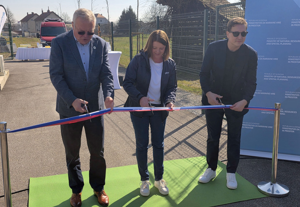 Three people cutting ribbon.