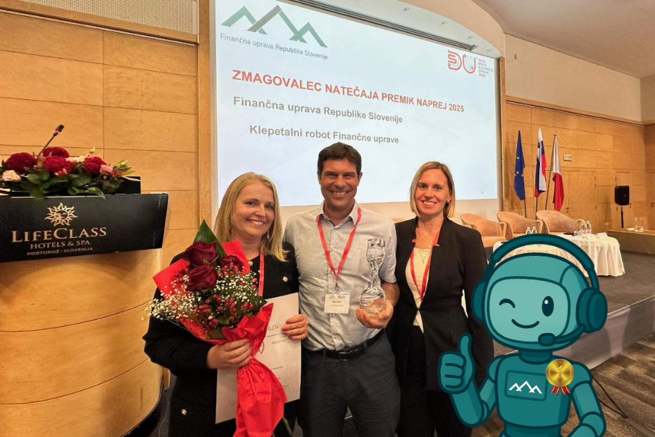 Trije ponosni uslužbenci Finančne uprave stojijo v dvorani. V rokah imajo nagrado poleg njih pa je kot fotomontaža dodana ikona Klepetalnega robotka z zlato medaljo.