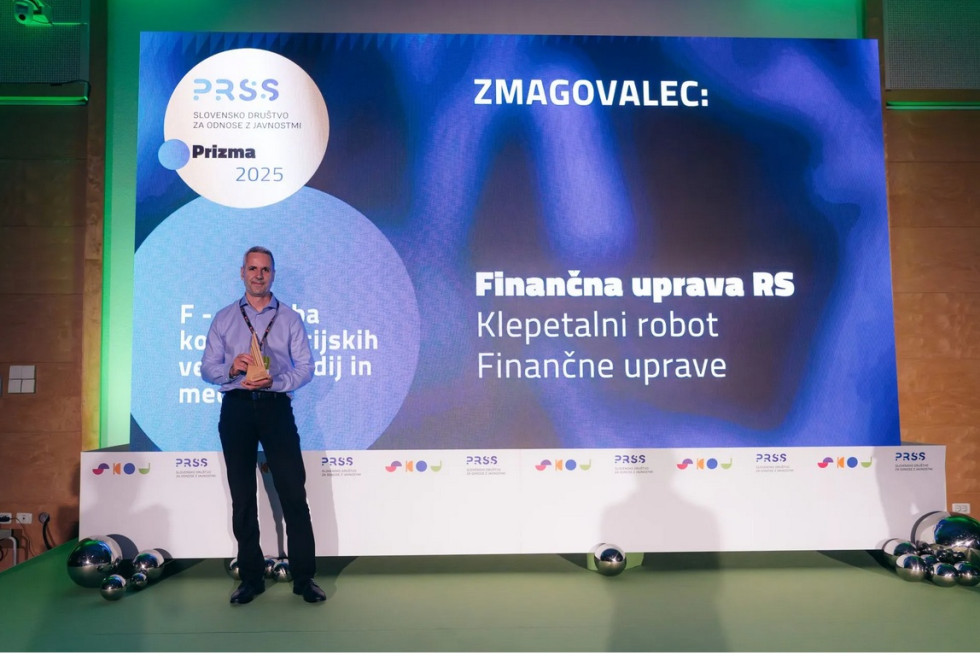 Predstavnik Finančne uprave Stojan Glavač na odro drži priznanje Prizma 2025
