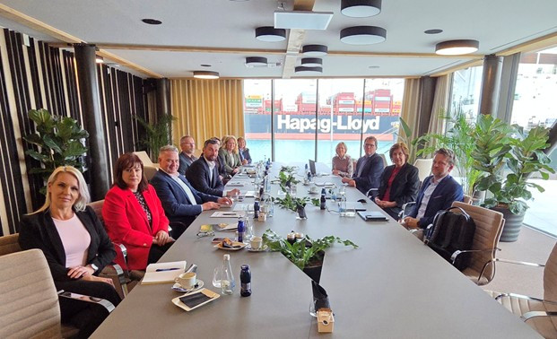 V večji pisarni za mizo sedijo predstavniki Finančne uprave in Luke Koper d.d. Skozi okno pisarne se vidi morje in ladja