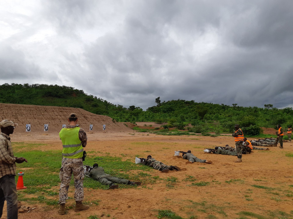 Vojaški inštruktorji nadzirajo strelsko urjenje malijskih oboroženih sil na peščenem strelišču.