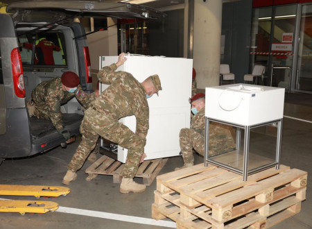 Pripadniki Slovenske vojske pred objektom urgence UKC nalagajo opremo laboratorija UKC iz kombiniranega vozila na transportno paleto.