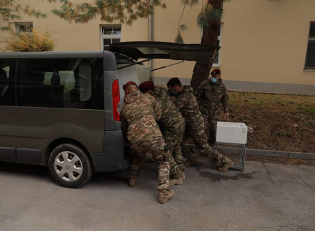 Pripadniki Slovenske vojske nalagajo opremo laboratorija UKC v kombinirano vozilo.