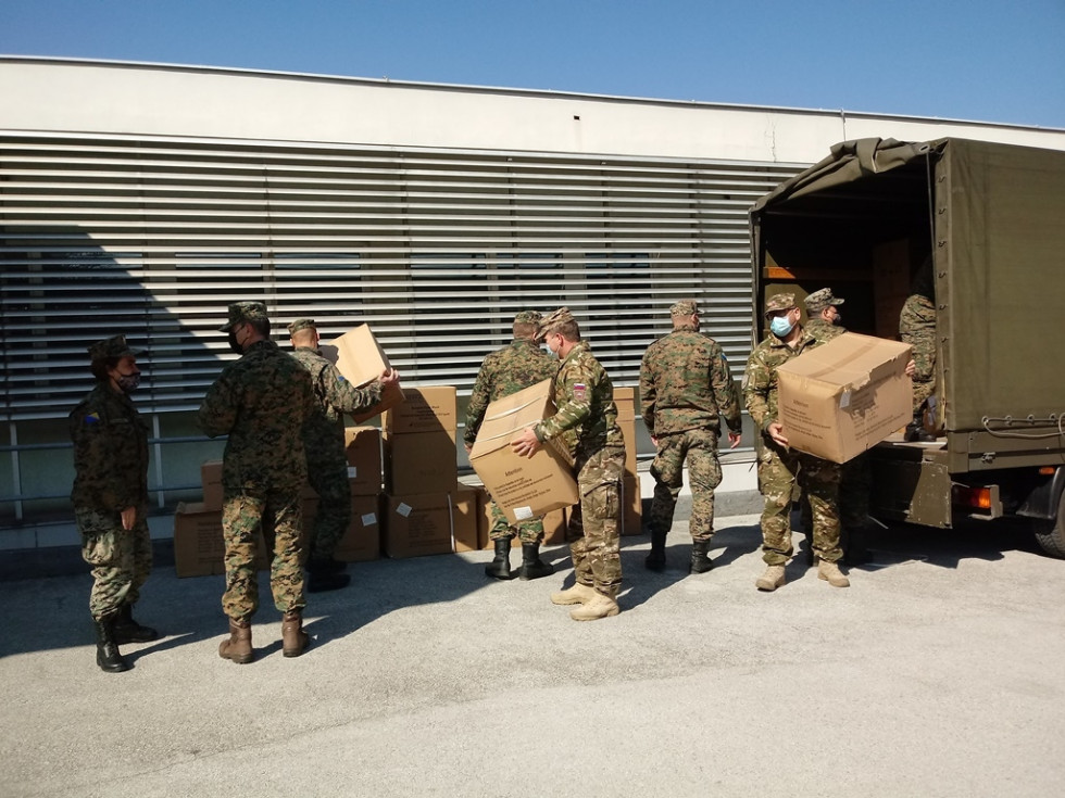 Vojaki Slovenske vojske  raztovarjajo donirani material s tovornega vozila.