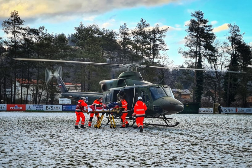 Na helikopter Slovenske vojske nalagajo obolelo osebo, ki potrebuje hitro nujno medicinsko pomoč.