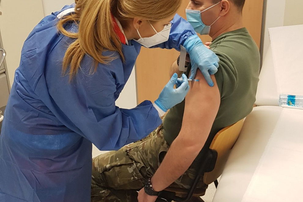 Pripadnik Slovenske vojske in medicinska sestra med postopkom cepljenja.