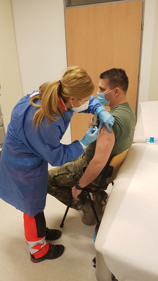 Pripadnik Slovenske vojske in medicinska sestra med postopkom cepljenja.