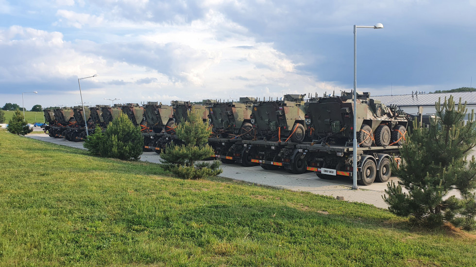 Parkirani vojaški tovornjaki na katere so naloženi lahka kolesna oklepna vozila Valuk.